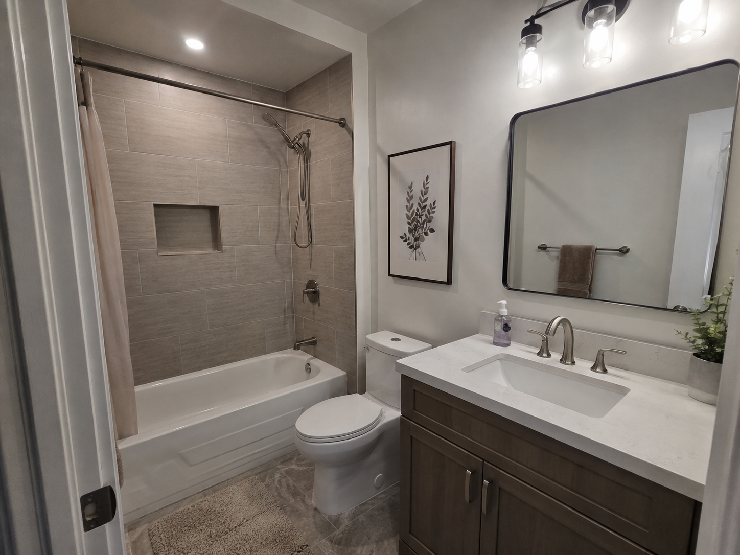 Family bathroom with tiled tub surround and quartz-topped vanity
